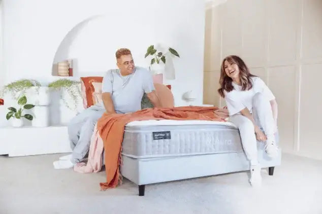 Two people enjoying a modern bedroom with a grey mattress and cozy bedding