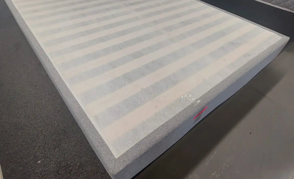 Factory direct mattress with striped top and grey edge on showroom floor