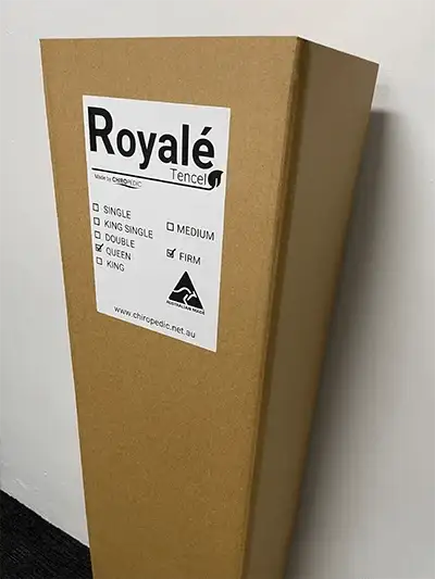 Mattress in a box packaging labeled Royale, queen and firm, against a white wall