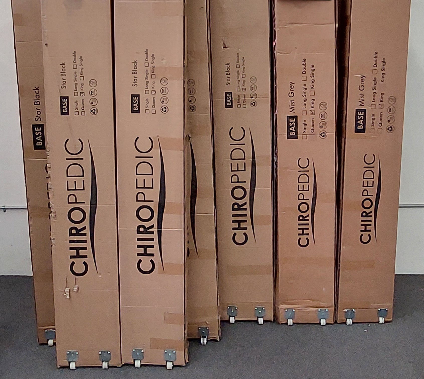Packaged mattress bases in boxes labeled Chiropedic on wheels, stacked indoors