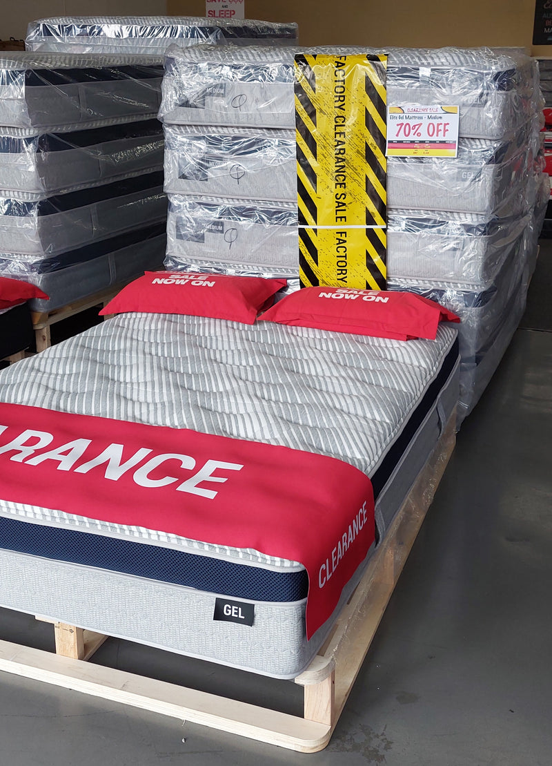 Gel mattress on display in clearance sale with stacked mattresses and 70% off sign