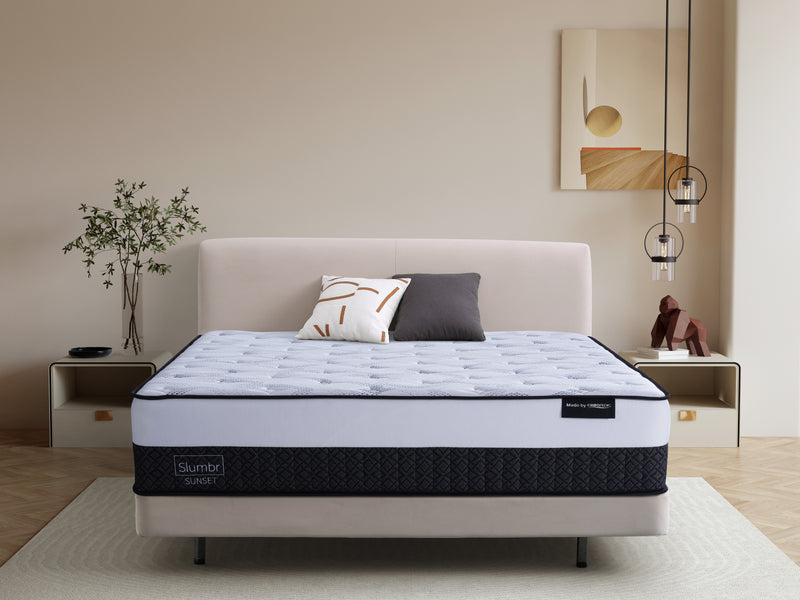 Modern bedroom with queen mattress on upholstered bed, decorative pillows, and bedside tables.