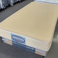 Single size commercial mattress with plain beige cover in showroom setting