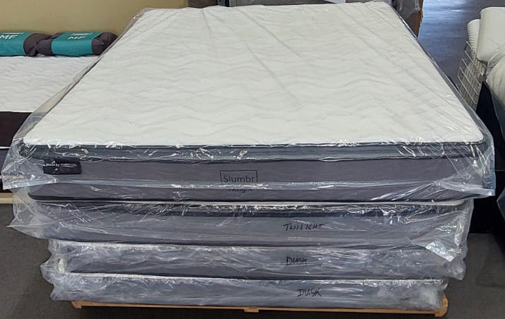 Stack of new queen mattresses wrapped in plastic on showroom floor