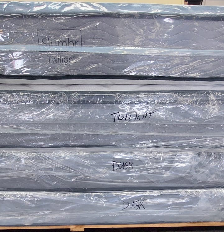 Stack of new mattresses wrapped in plastic, labeled Twilight and Dusk, on a pallet