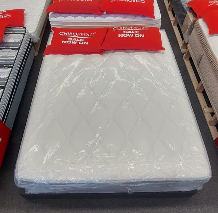 Factory direct mattress in plastic cover with diamond quilt pattern on showroom floor