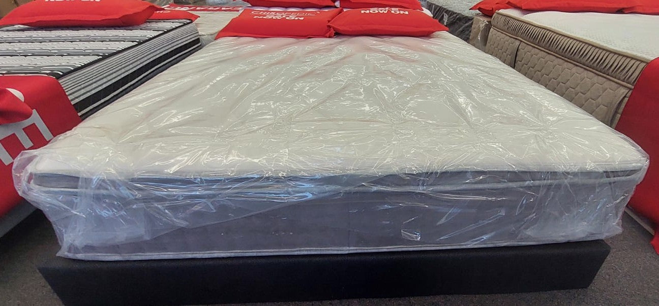 Factory-direct mattress wrapped in plastic on display with red sale signs