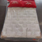 Factory-direct queen mattress wrapped in plastic with red sale pillows on showroom floor