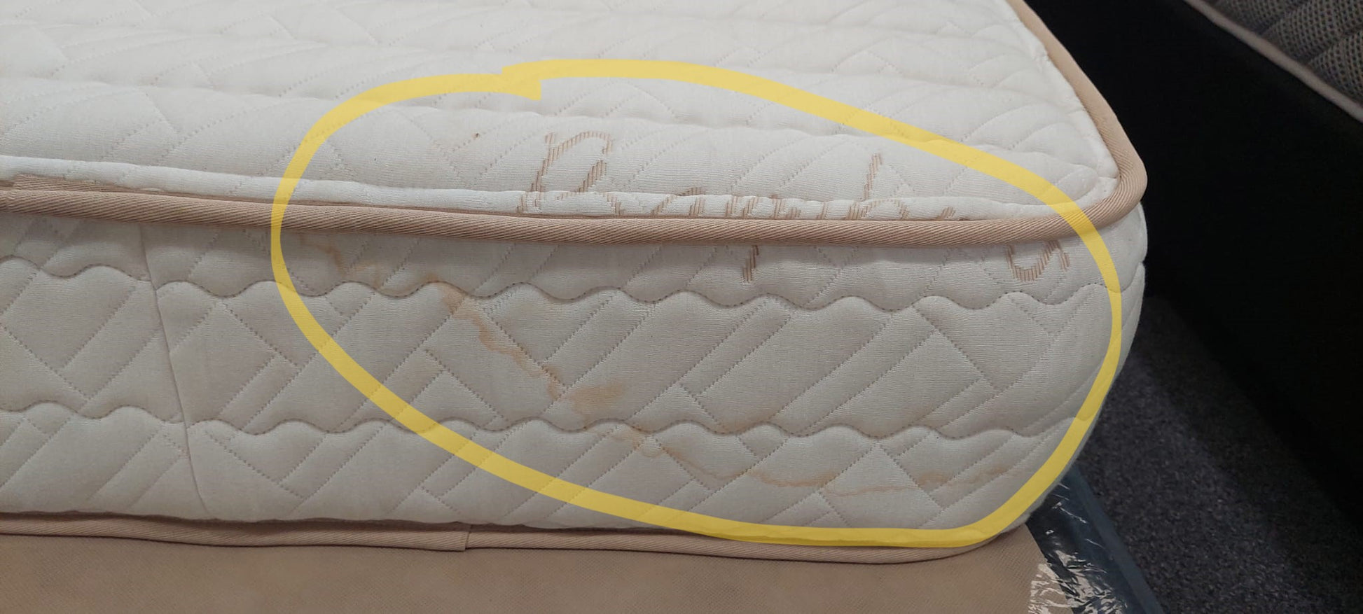 Close-up of a mattress with visible stains on the side, mattress fabric and stitching detail