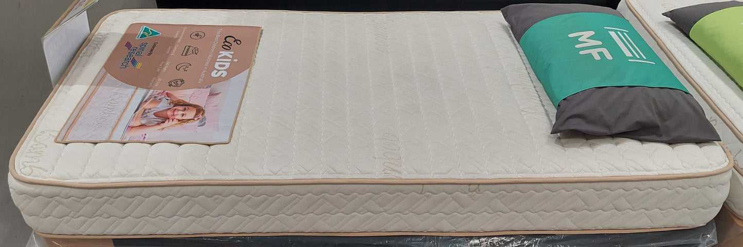 Kids mattress with quilted white cover, product info card, and decorative pillow