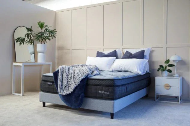 Modern bedroom with a plush queen mattress, upholstered bed base, pillows, and cozy blanket