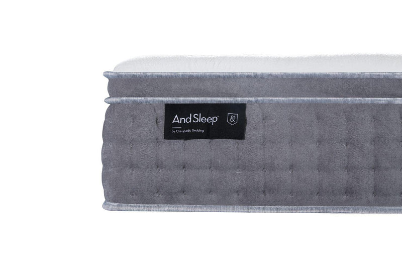 Close-up of a grey quilted mattress side with And Sleep label, showing plush top layer